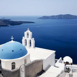 a blue domed church overlooking the mediterranean in satorini