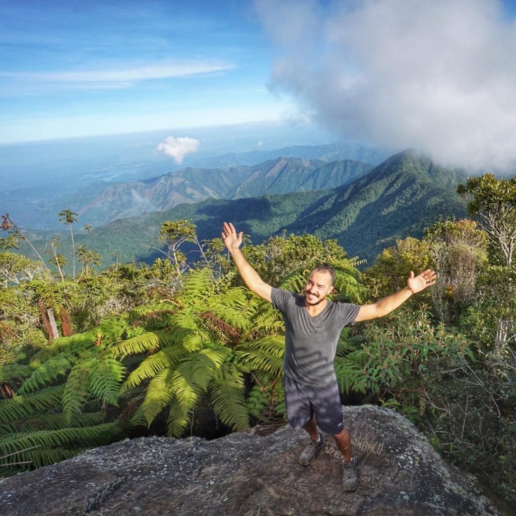 a man celebrates climbing to the top of el pico turquino cuba