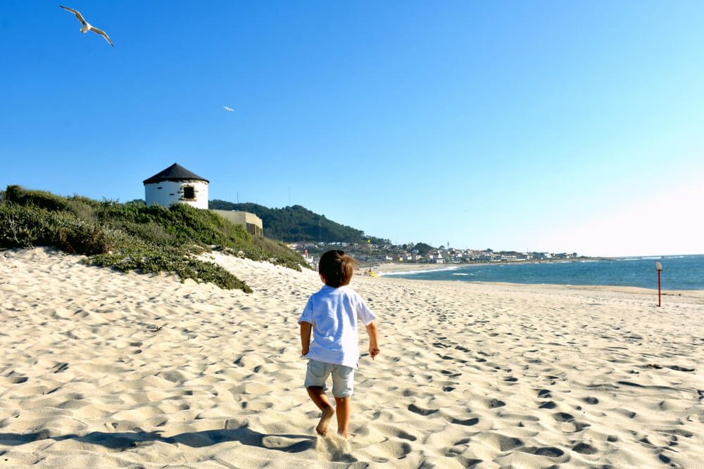 A kid playing in the sand of one the beaches of Portugal, next to the town of Viana do Castelo